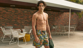 A.P.C. Men's Other Accessories - Man wearing patterned swim trunks in a backyard patio.