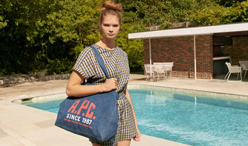 A.P.C. Women's Bags - Woman wearing checkered dress holding denim tote by a pool.